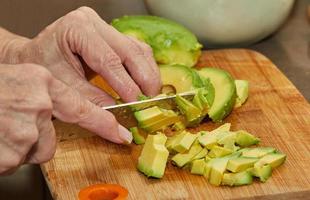 Cook schneidet reife Avocado in Scheiben für die Salatzubereitung