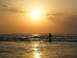 Seelandschaft mit einem herrlichen Sonnenuntergang und der Silhouette eines Mannes, der auf dem Meer spaziert. foto