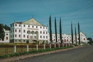 Bento Goncalves, Brasilien - 10. Juli 2019. Straße mit der Fassade des Salton Winery Headquarters hinter einem Zaun und Gärten in der Nähe von Bento Goncalves. eine freundliche Landstadt, die für ihre Weinproduktion bekannt ist. foto