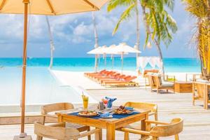 Luxus-Resort-Hotel am Pool, Restaurant im Freien am Strand, Meer und Himmel, tropisches Inselcafé, Tische, Essen. Sommerurlaub oder Urlaub, Familienreisen. Palmen, Infinity-Pool, Cocktails, Relax