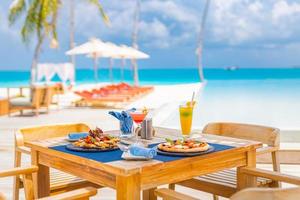 Luxus-Resort-Hotel am Pool, Restaurant im Freien am Strand, Meer und Himmel, tropisches Inselcafé, Tische, Essen. Sommerurlaub oder Urlaub, Familienreisen. Palmen, Infinity-Pool, Cocktails, Relax