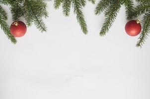 Ansicht von oben, zwei rote Kugeln und Weihnachtsbaumzweige auf weißem Hintergrund. foto