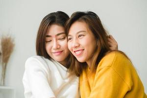 schöne junge asiatische frauen lgbt lesbisches glückliches paar sitzen auf dem bett, umarmen und lächeln zusammen im schlafzimmer zu hause. lgbt lesbisches paar zusammen drinnen konzept. schöne Zeit zu Hause verbringen. foto