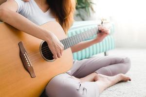 Asiatisches junges lesbisches Paar spielt Gitarre für ihren Geliebten mit Liebesmoment im Schlafzimmer, umgeben von warmem Sonnenlicht. LGBT-Paare haben einen Liebesmoment zusammen im Bett. LGBT-Liebesmoment-Konzept. foto