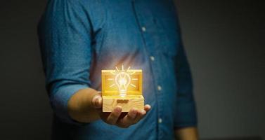 Mann hält eine hölzerne Schatzkiste Glühbirne der Weisheit ununterbrochene Gedanken brillantes Konzept foto