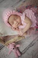 kleines Baby in rosa Kleidung gehüllt mit einem Verband auf dem Kopf liegt schläft auf weißem Kissen foto