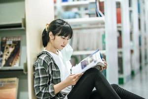 Eine Frau sitzt in der Bibliothek und liest ein Buch. foto