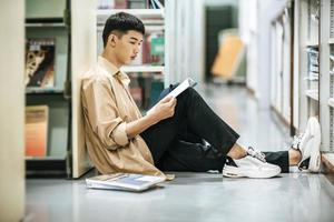 Ein Mann sitzt in der Bibliothek und liest ein Buch. foto