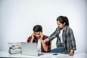 Frauen bringen Männern bei, wie man mit Laptops am Arbeitsplatz arbeitet. foto