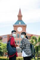 Studentinnen und Studenten tragen Masken und stehen vor der Universität. foto