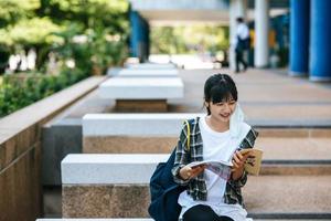 Studentin sitzt auf der Treppe und liest ein Buch. foto