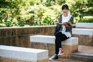 Studentin sitzt auf der Treppe und liest ein Buch. foto
