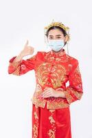 Frauen tragen Cheongsam-Anzug und Maske zeigen den besten Weg zum Einkaufen zum Schutz von Krankheiten foto