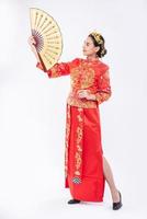Frau trägt Cheongsam-Anzug Zeigen Sie den chinesischen Handfan auf einem großen Ereignis im chinesischen Neujahr foto