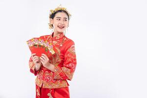 Frau trägt Cheongsam-Anzug Lächeln, um Geschenkgeld von der Familie im chinesischen Neujahr zu bekommen foto
