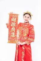 Frau trägt Cheongsam-Anzug froh, die chinesische Grußkarte vom Chef im chinesischen Neujahr zu bekommen foto