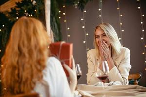 lesbisches Paar beim Abendessen in einem Restaurant. Mädchen gibt ihrem Schatz ein Geschenk foto