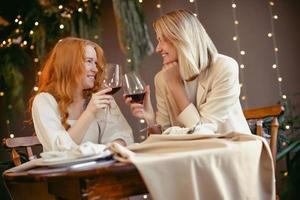 lesbisches Paar beim Abendessen in einem Restaurant. Mädchen trinken Wein und reden foto