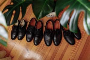 Herrenschuhe Konzepte schwarze Lederschuhe auf dem Boden in der Nähe der Zimmerpflanze platziert. vier Paar Herrenstiefel foto