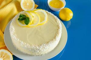 Zitronenkuchen mit Kokosflocken auf blauem Hintergrund. zartes Dessert mit Sahne. foto