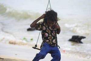 Sorong, West Papua, Indonesien, 12. Dezember 2021. Ein junges Mädchen spielt Schaukel am Rande des Strandes