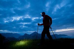 Wandern Sie in den Bergen mit einer elektrischen Taschenlampe am frühen Morgen foto