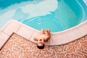 glücklicher kleiner Junge im Pool beim Eisessen foto