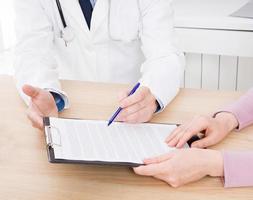 Arzt mit Patient in Arztpraxis unterzeichnen einen Vertrag. Gesundheitskonzept. Krankenversicherung. foto