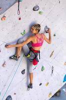 eine Frau klettert an einer Kletterwand foto