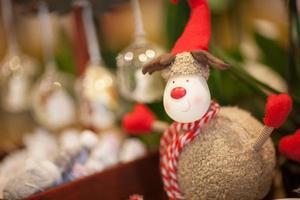 Kuscheltier Weihnachtsrentier mit rotem Schal und Mütze auf verschwommenem Hintergrund foto