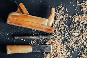 altes Handflugzeug, Bohrer und Meißel mit Holzspänen auf schwarzem Hintergrund. altes Handwerkzeug für die Holzbearbeitung. kopieren, leerer Platz für Text foto