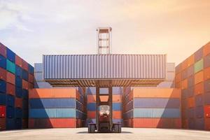 Gabelstapler heben Frachtcontainer im Versandhof für Transportimport, -export, Logistikindustrie mit Containerstapel im Hintergrund