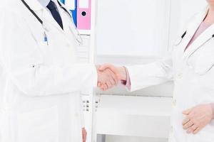 handeln. Konzept der Zusammenarbeit in der Medizin. Nahaufnahme Foto von zwei Ärzten Händeschütteln. Krankenversicherung.