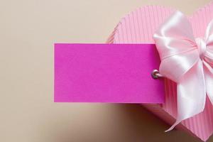 leere Karte mit rosa herzförmiger Geschenkbox und Schleife foto