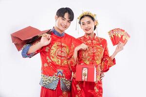 Der Mann und die Frau, die Cheongsam tragen, bekommen die rote Tasche, Geschenkgeld und ein Geschenk von ihren Verwandten am traditionellen Tag foto