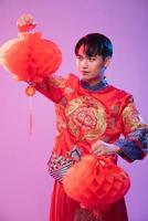 Mann trägt Cheongsam-Show, schmückt rote Lampe, um im chinesischen Neujahr einzukaufen foto