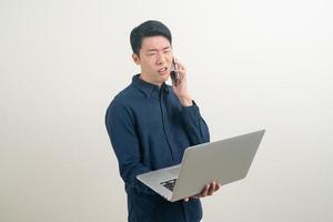 asiatischer Mann spricht Smartphone oder Handy und Hand hält Laptop foto