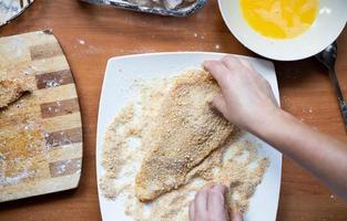 das Schnitzel panieren. Zubereitung eines traditionellen polnischen Abendessens in Hausmannskost. Sicht von oben. foto