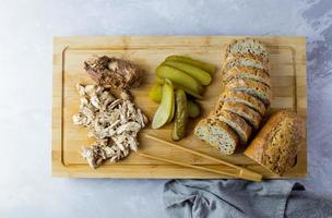 Pulled Chicken mit Brot und eingelegter Gurke. Ansicht von oben. foto