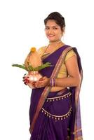 indische traditionelle frau, die einen traditionellen kupferkalash hält, indisches festival, kupferkalash mit kokos- und mangoblatt mit blumendekoration, unverzichtbar in hindu-puja. foto