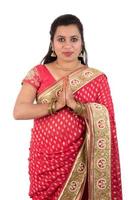 schönes indisches mädchen in einem traditionellen sari mit willkommenem ausdruck einladend, gruß namaste foto
