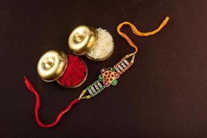 Raksha Bandhan Hintergrund mit einem eleganten Rakhi, Reiskörnern und Kumkum. ein traditionelles indisches Armband, das ein Symbol der Liebe zwischen Brüdern und Schwestern ist. foto