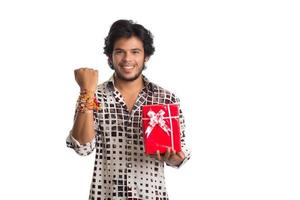 Mann oder Bruder, der anlässlich des Raksha-Bandhan-Festivals Rakhi auf seiner Hand mit Einkaufstüten und Geschenkbox zeigt. foto