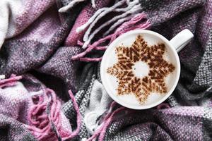 Kaffee mit Schneeflockenmuster auf einem warmen Wollplaid foto