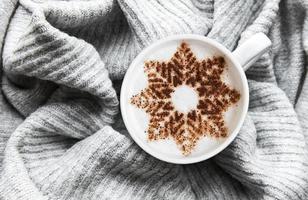 Kaffee mit Schneeflockenmuster auf einem warmen Strickpullover