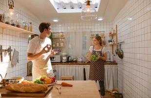 junges Paar bereitet ein Frühstück in der Küche mit einem lustigen Lächeln und Glück zu foto