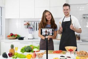 Junges kaukasisches Paar, das Blogger ist und Menschen beibringt, gesundes Essen über die Smartphone-Kamera zu kochen. Familie zusammen Konzept foto