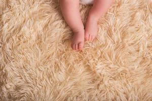 nackte Beine eines Neugeborenen auf einer flauschigen, leichten, tonnenschweren, warmen Decke. süße neugeborene Babyfüße hautnah foto