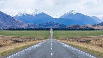 Panoramablick auf die lange gerade offene eisige Straße, die in Richtung Berge auf der Südinsel Neuseelands führt foto