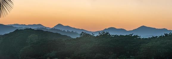 Sonnenuntergang über den Bergen mit Fluss und Palme foto